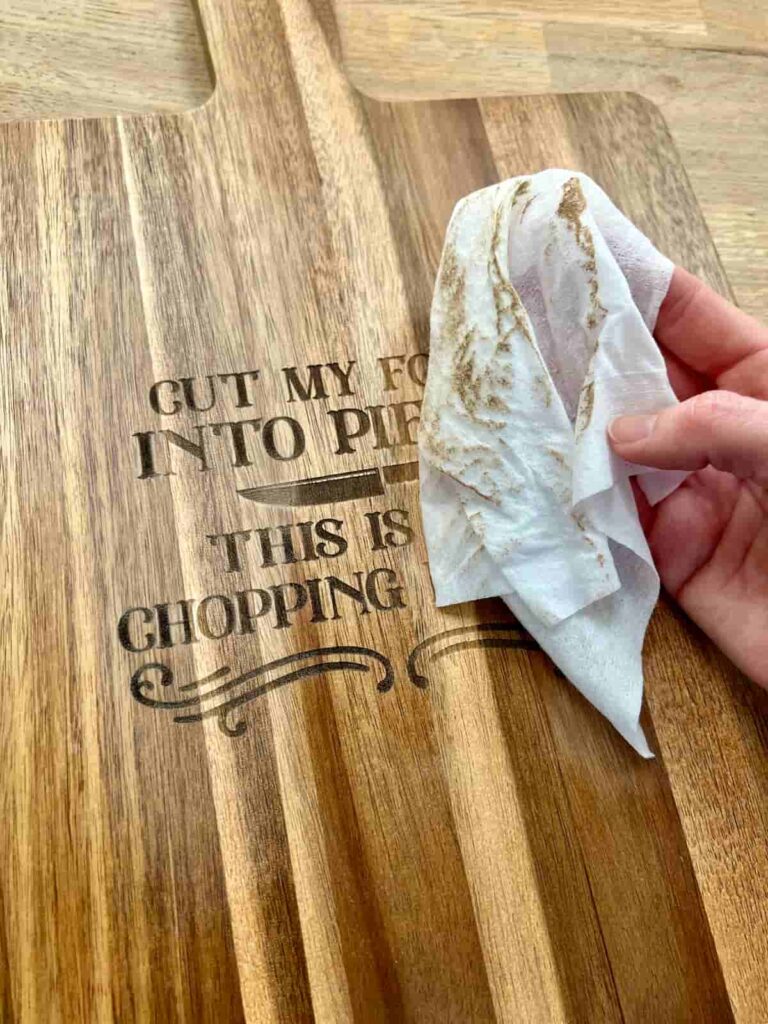image shows removing sanding and engraving dust from chopping board with wet wipe.