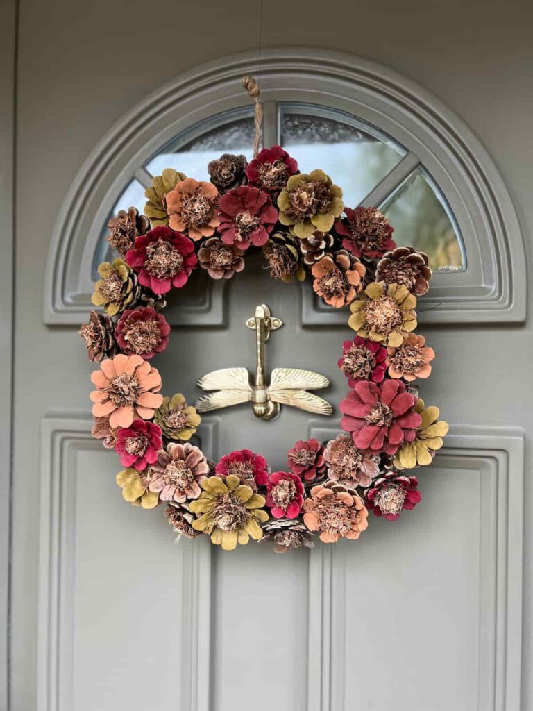 image shows painted pinecone wreath on a door.