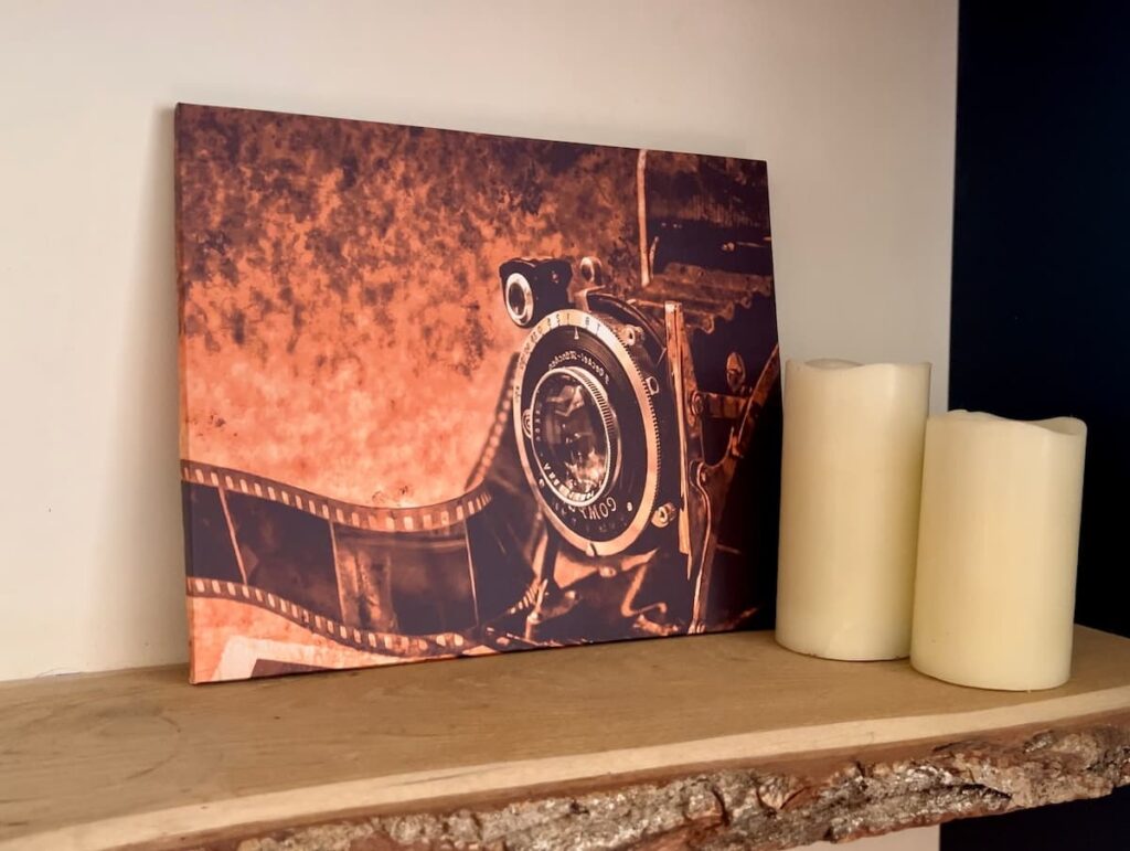 image shows decoupaged poster on a shelf next to candles.