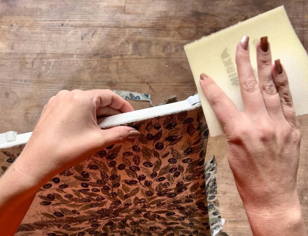 image shows hand sanding edge of a canvas.