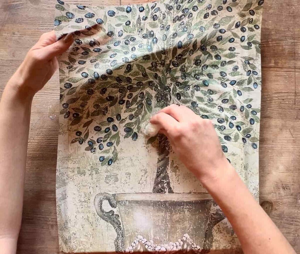 image shows smoothing out decoupage paper with plastic wrap.