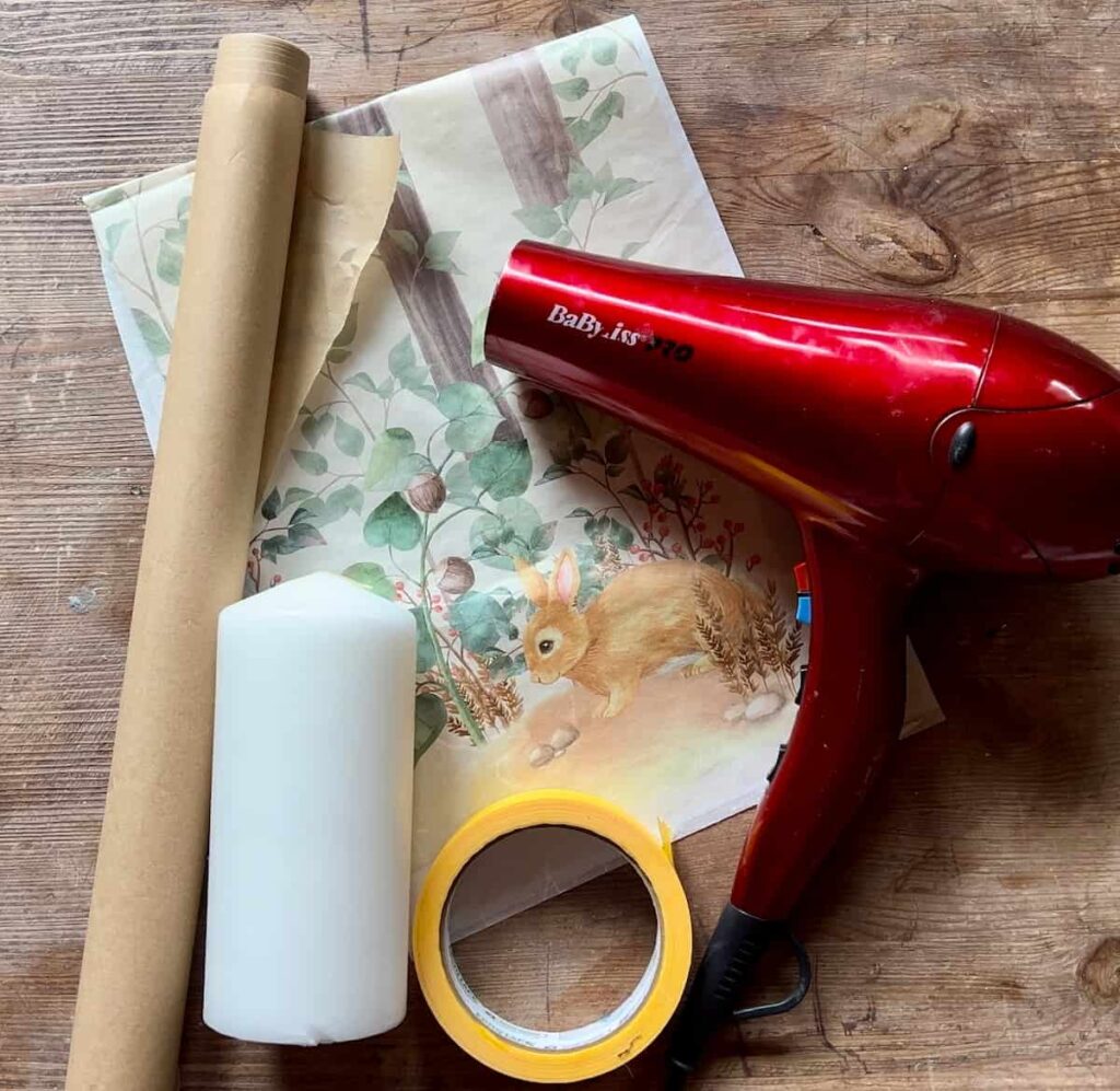 image shows hairdryer, candle, decoupage paper and parchment paper lying on surface.