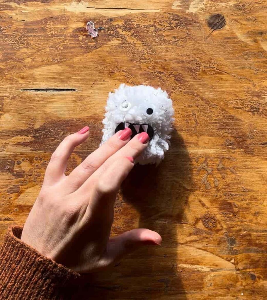 image shows glueing mouth to white pom pom monster.