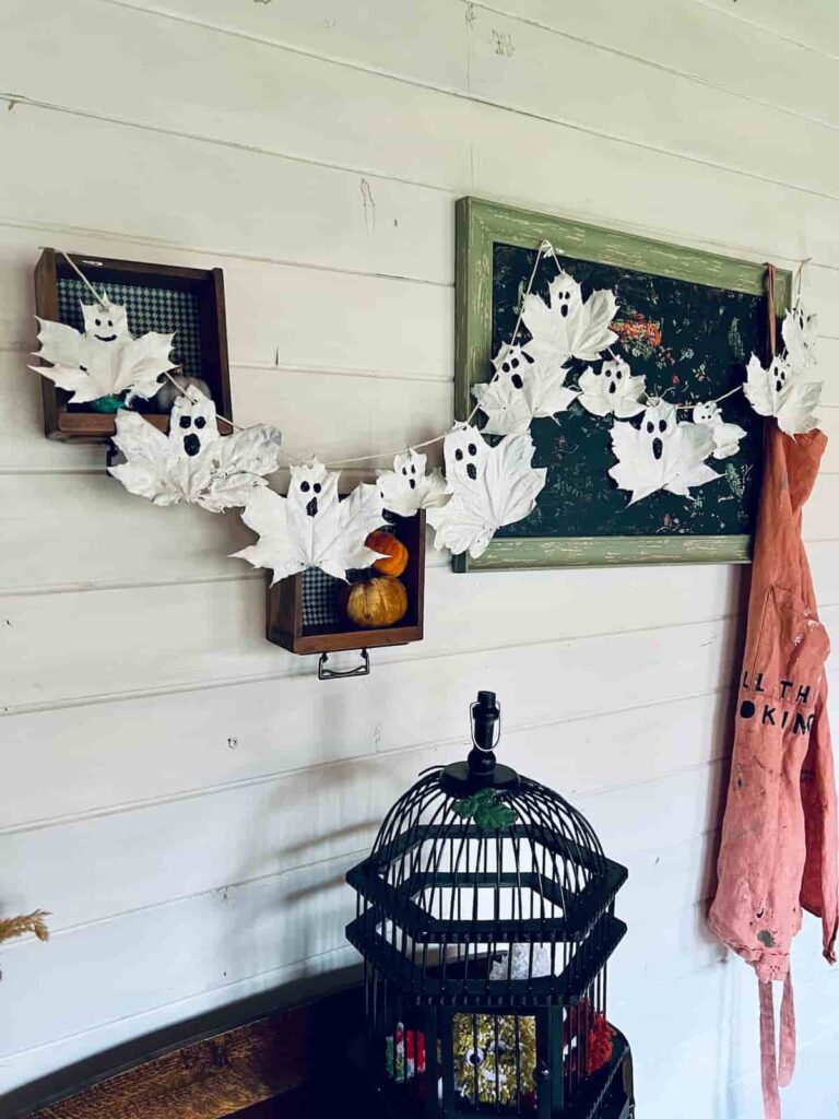 image shows halloween garland of leaf ghosts hanging on wall.