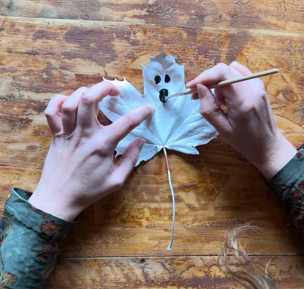 image shows painting face onto leaf ghost with black paint.