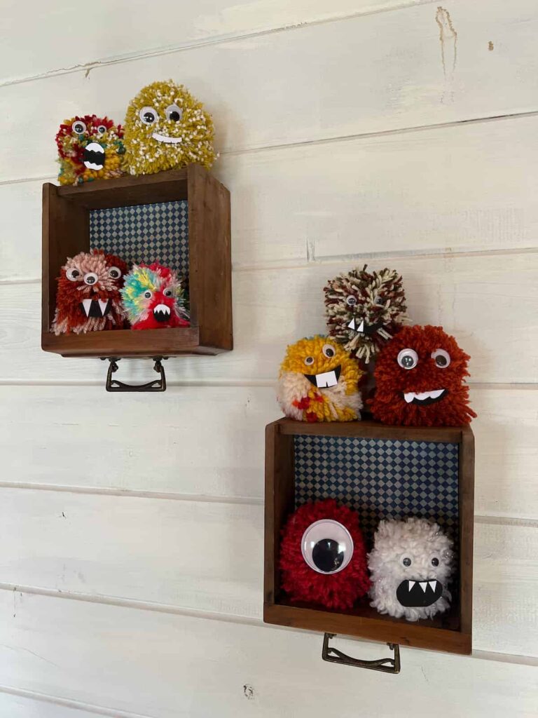 image shows two shelves with different coloured halloween pom pom monsters.