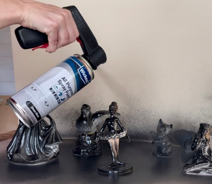 image shows spray painting figurines black.