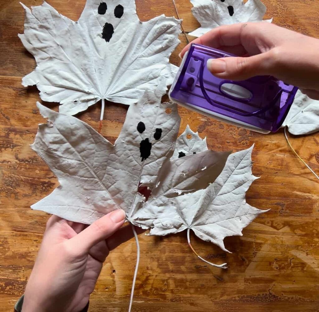 image shows using hole punch to make hole in top of leaf ghost.