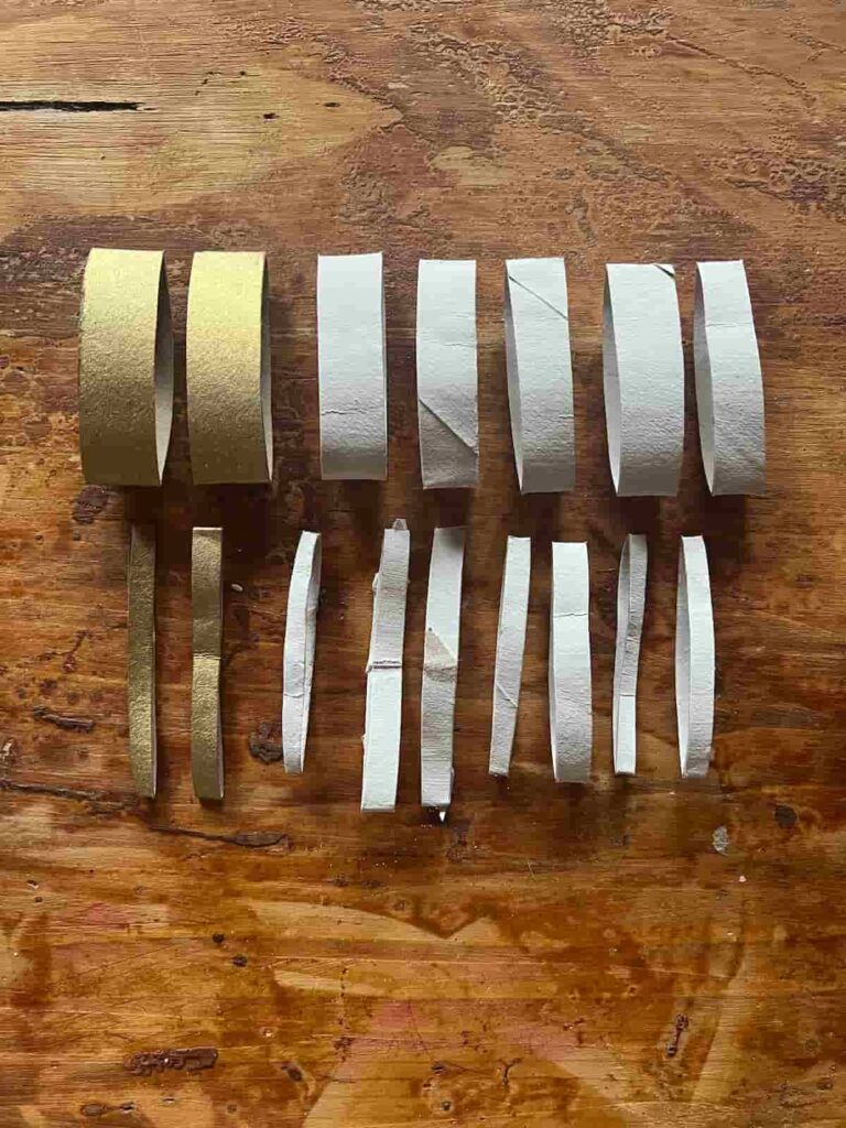 image shows gold and white painted toilet paper rolls.