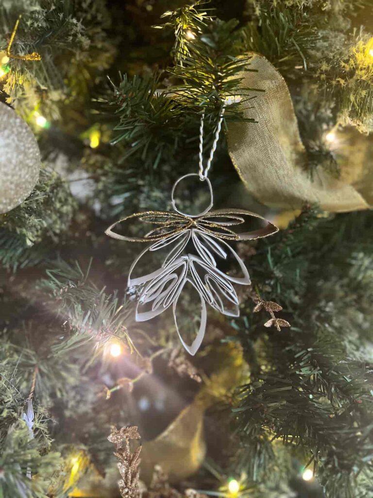 image shows angel made from toilet paper rolls in front of tree.