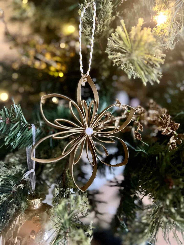 image shows gold tree ornament with pearl in the middle.