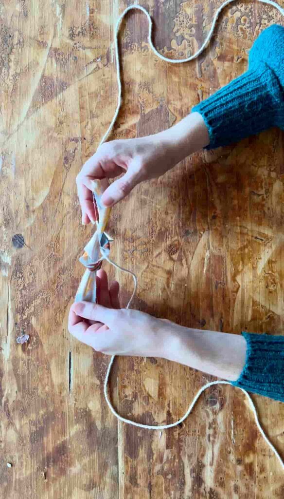 image shows hands attaching fabric to string.