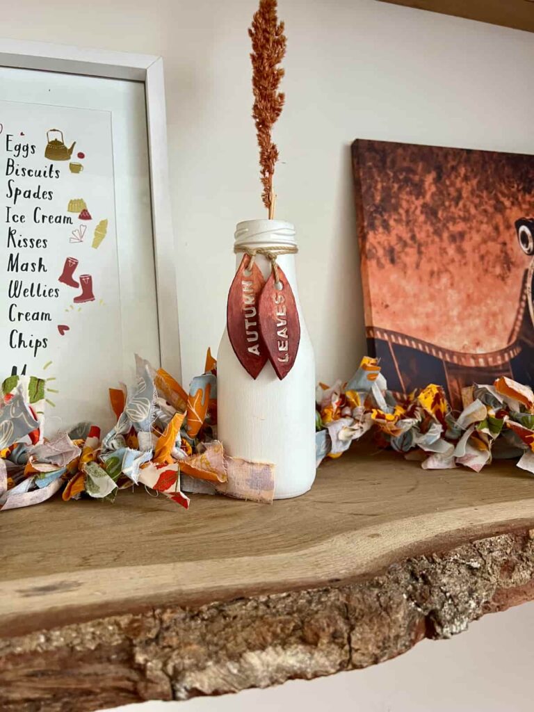 image shows rag garland on a shelf behind a bottle.