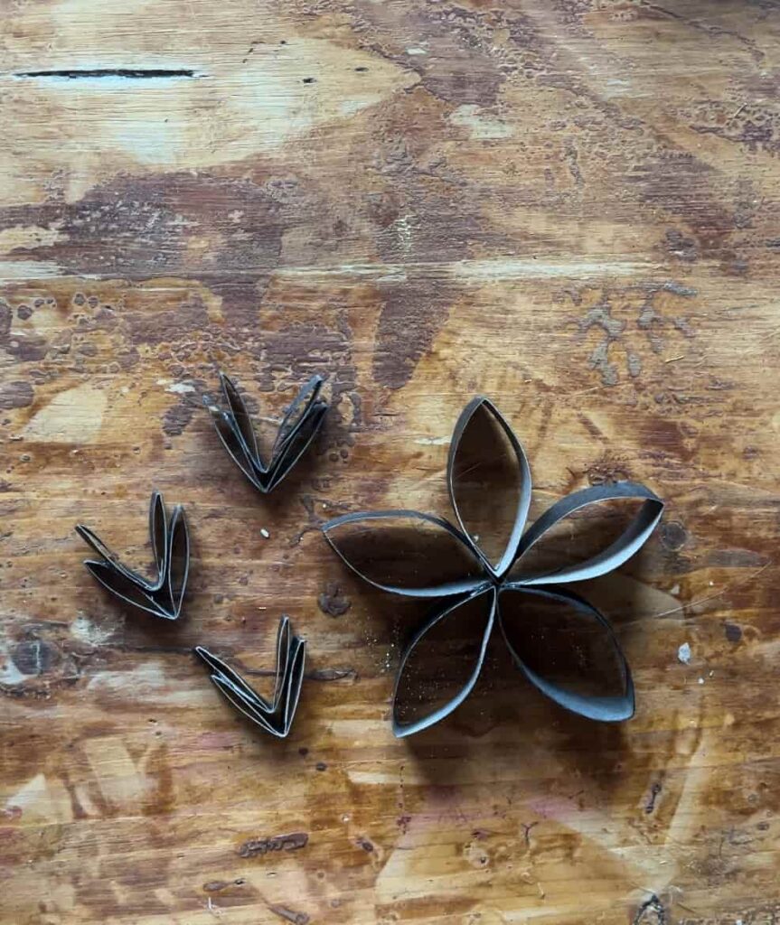 image shows snowflake made from toilet paper roll on table.