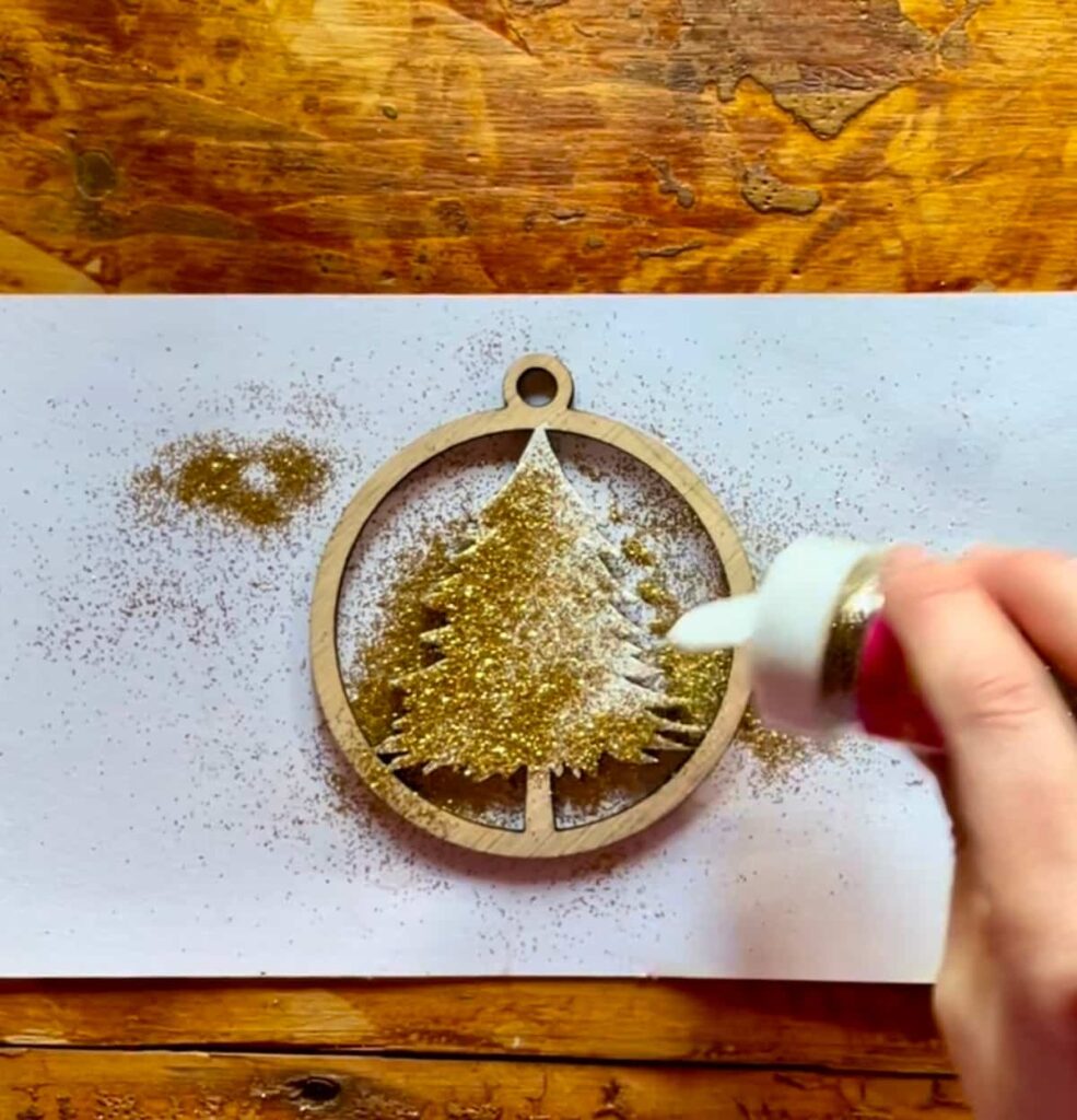 image shows adding gold glitter to laser cut ornament.