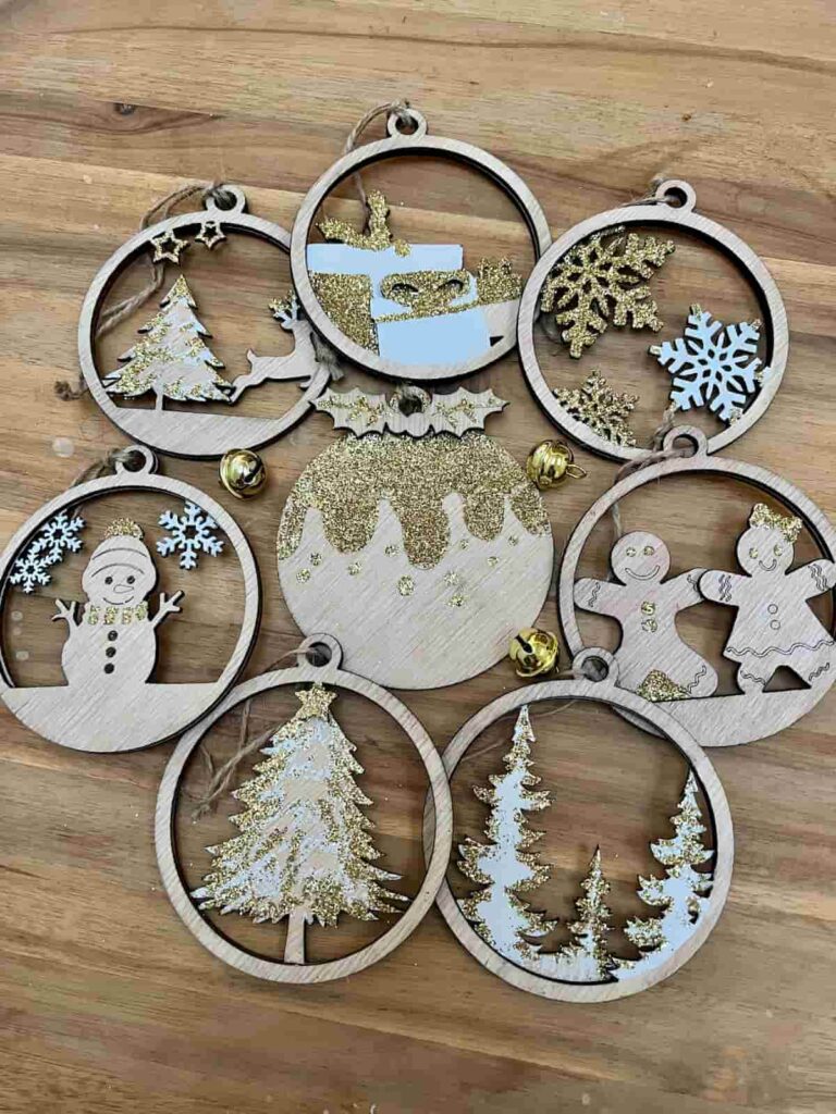 image shows 8 laser cut ornaments decorated with paint and glitter.