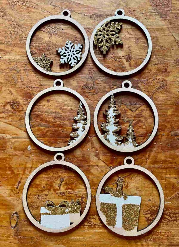 image shows pairs of laser cut ornaments decorated with paint and glitter.