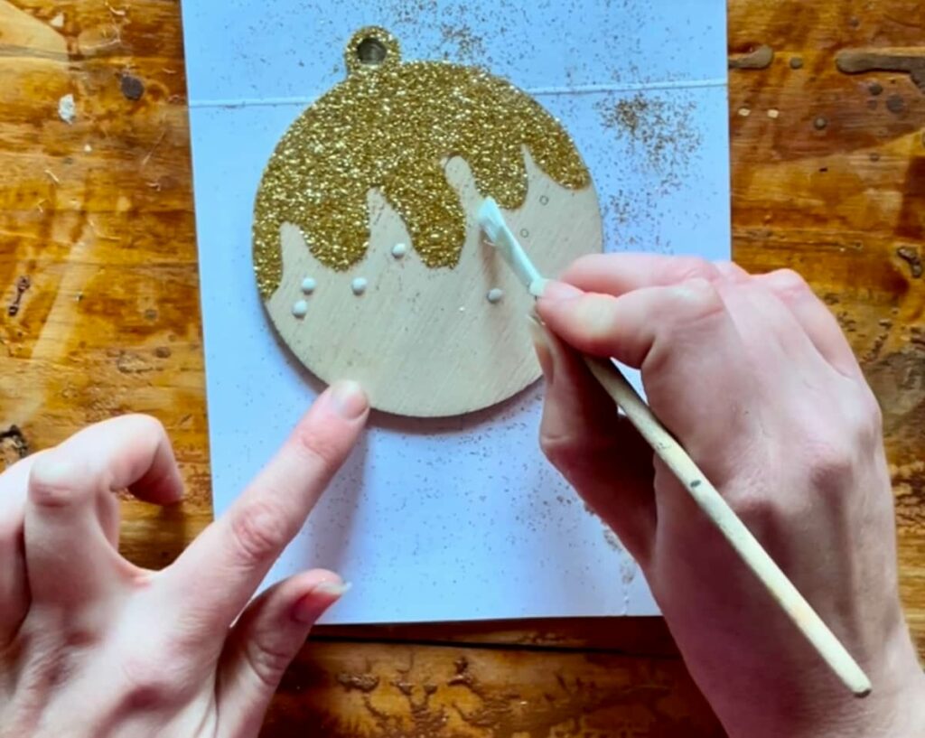 image shows decorating christmas pudding laser cut ornament with glitter.