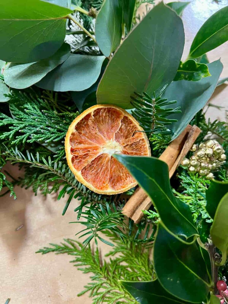 image shows orange slice and cinnamon stick on wreath.