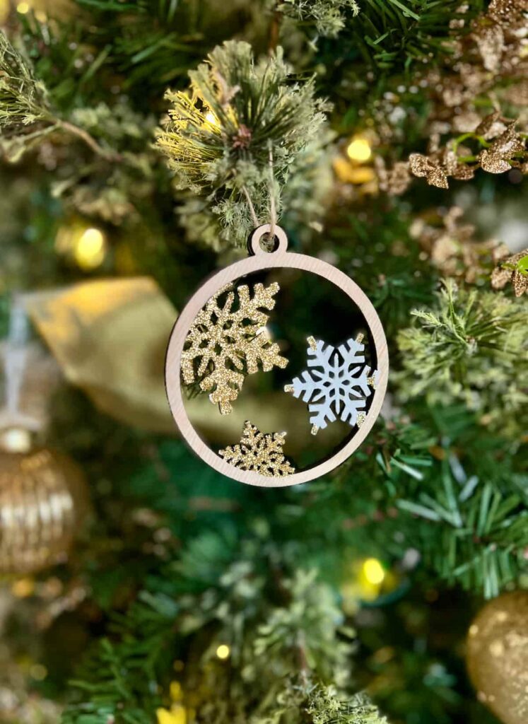 image shows laser cut snowflake ornament on a tree.