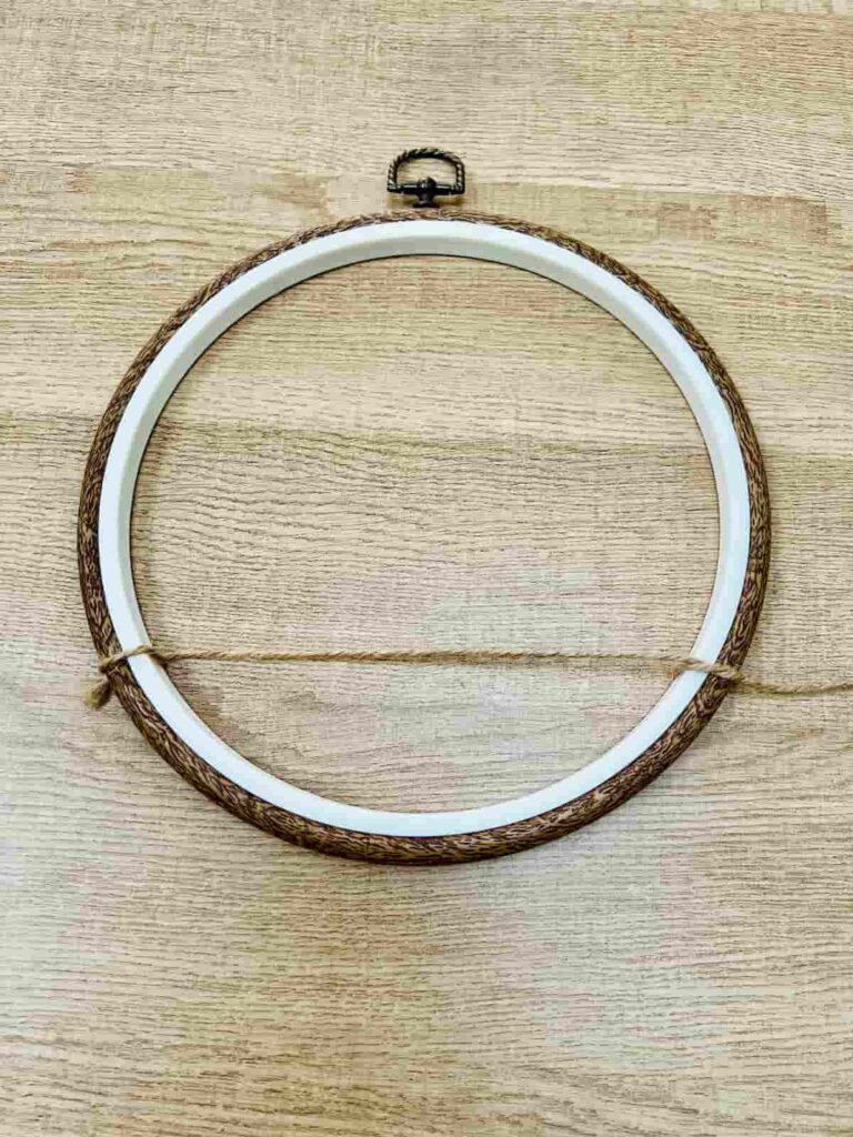 image shows first line of string attached to embroidery hoop.