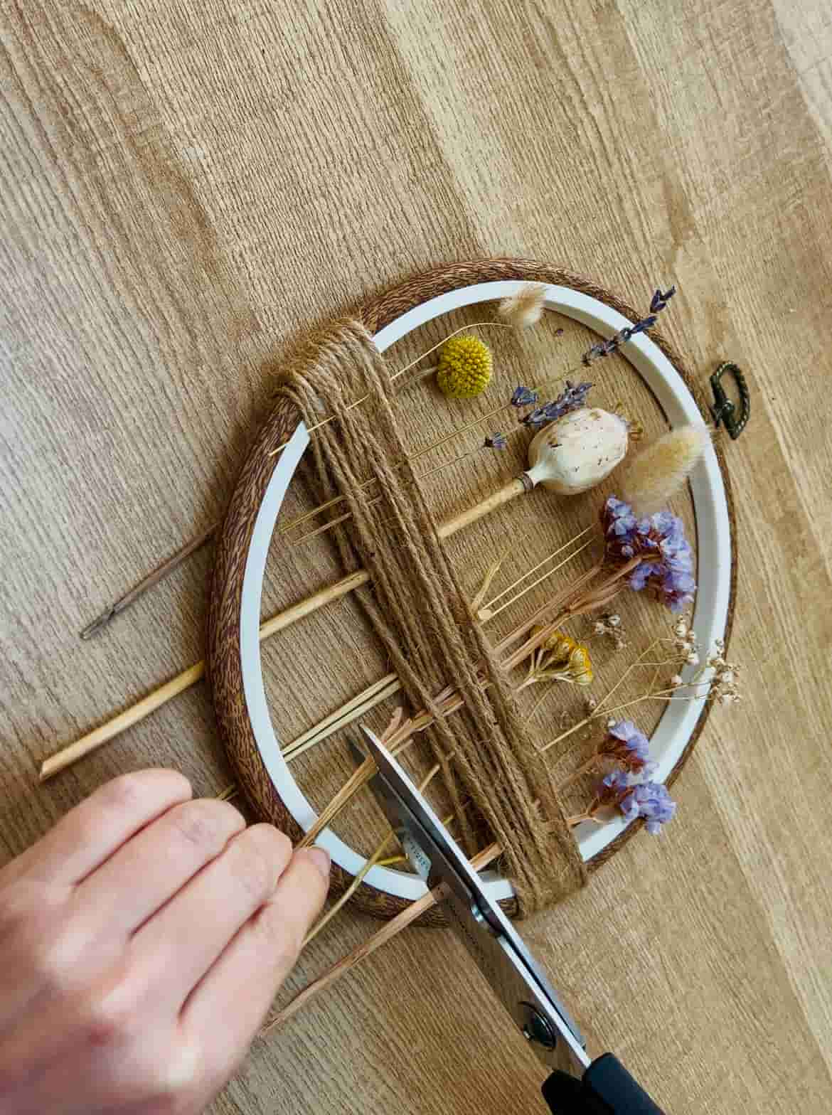 image shows cutting stems of flowers on embroidery hoop.