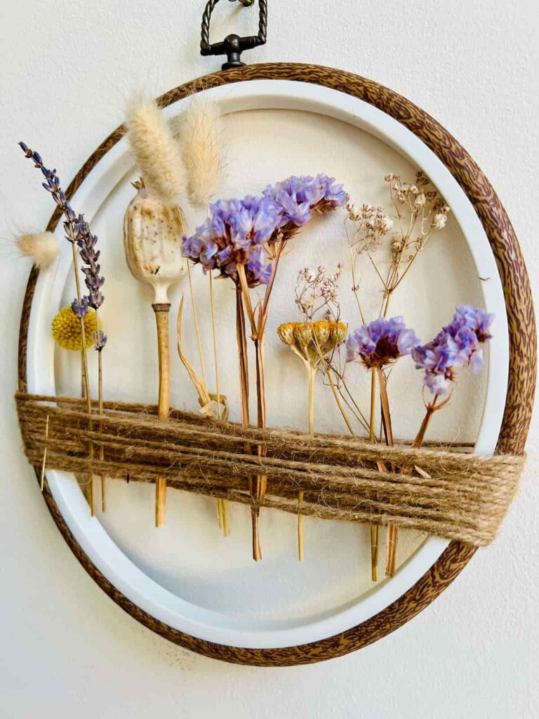 image shows embroidery hoop with dried flowers attached with string.