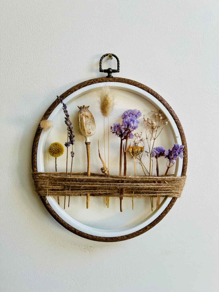 image shows embroidery hoop with dried flowers attached with string.