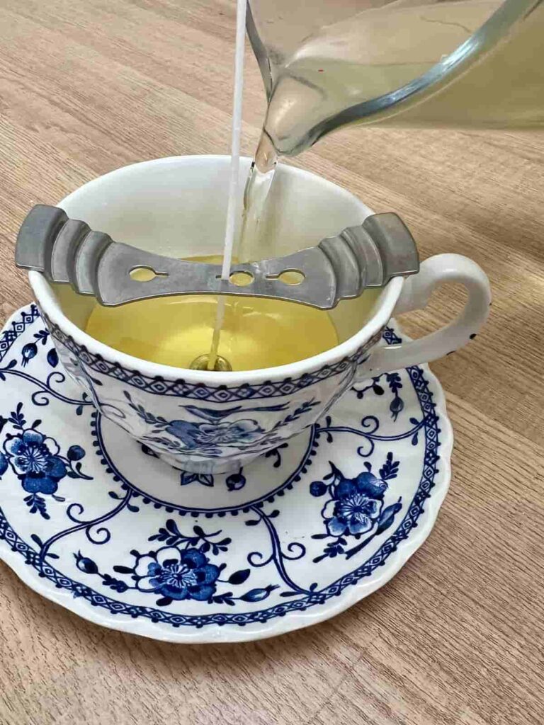 image shows pouring melted soy wax into tea cup.