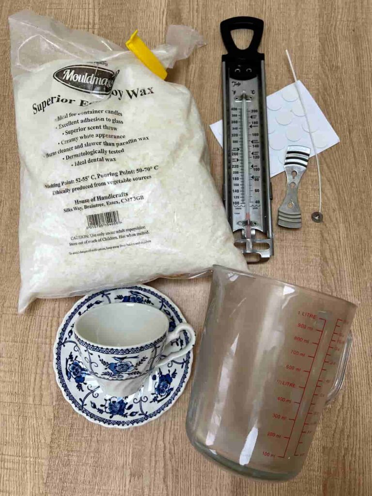 image shows soy wax, a measuring jug, thermometer, wicks and a tea cup.