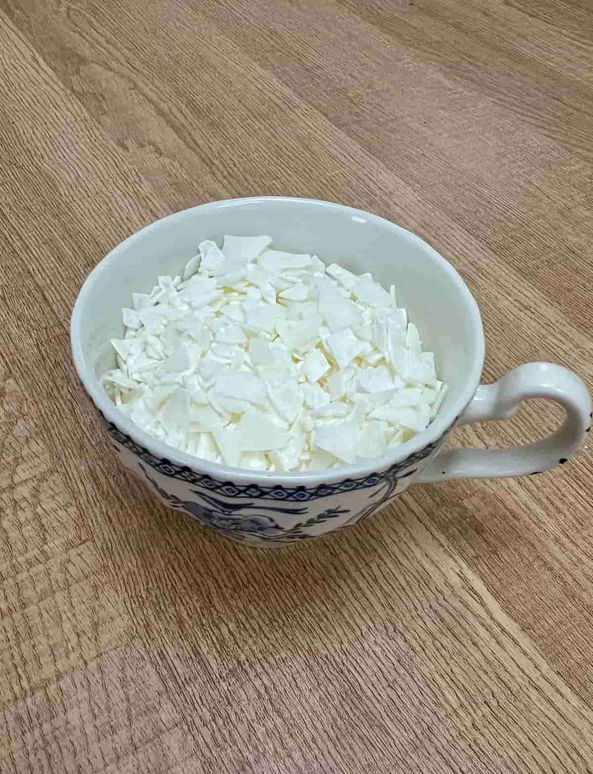 image shows tea cup filled with soy wax flakes.