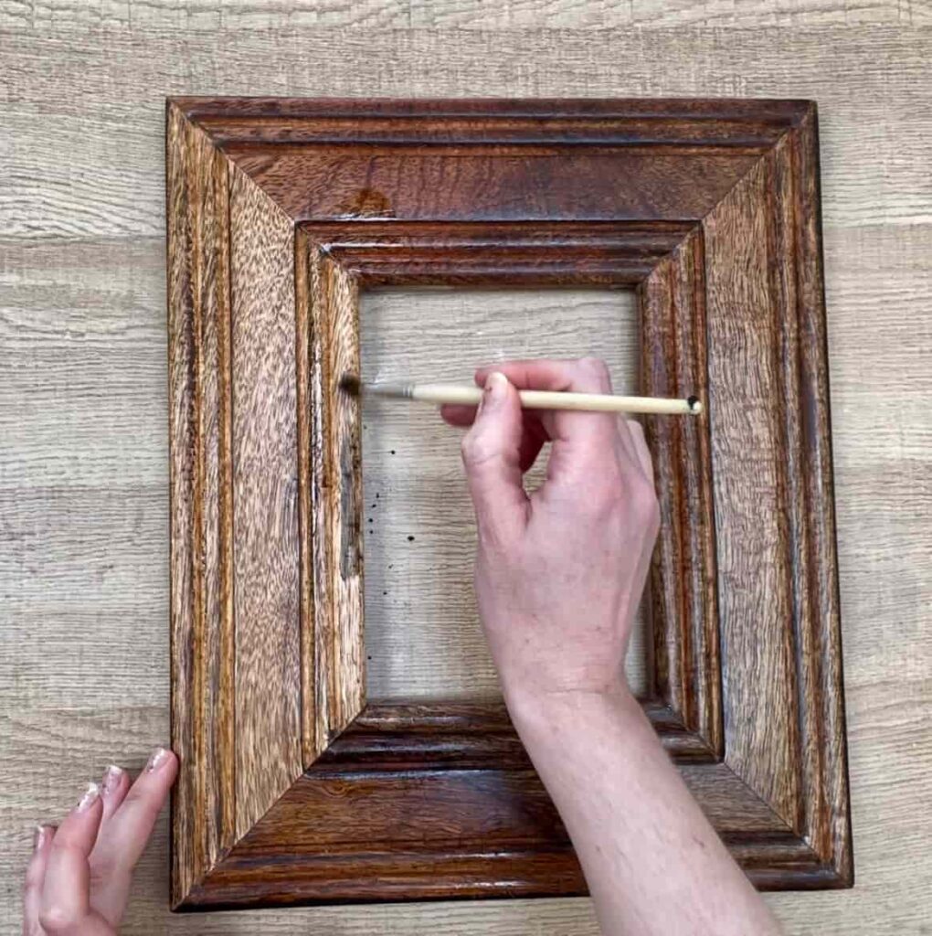 image shows applying wood stain to sanded photo frame.