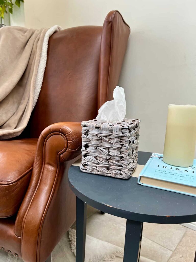 image shows tissue box cover on a table next to a brown chair.