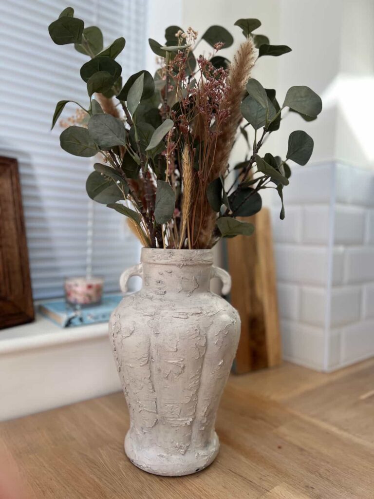 image shows a painted glass vase with flowers.