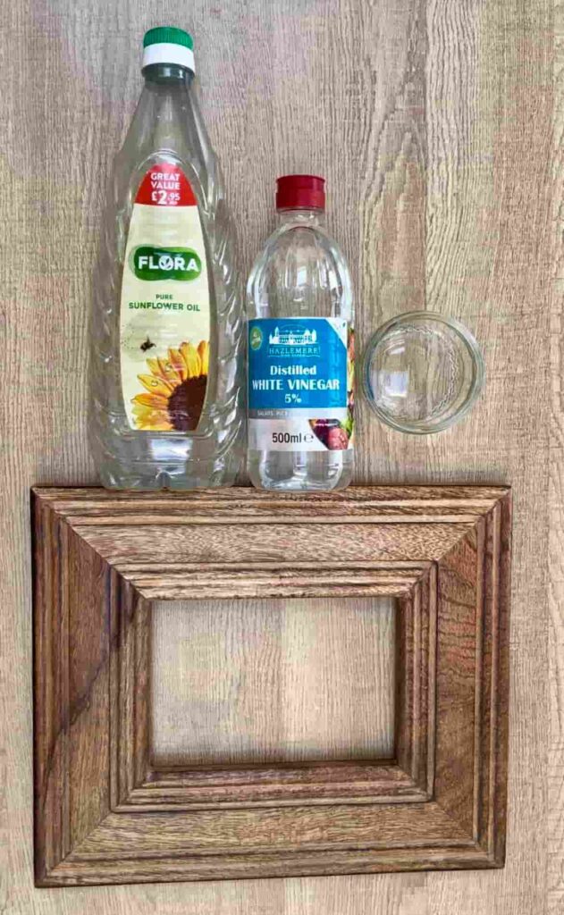 image shows a wooden photo frame, a bottle of oil and vinegar.