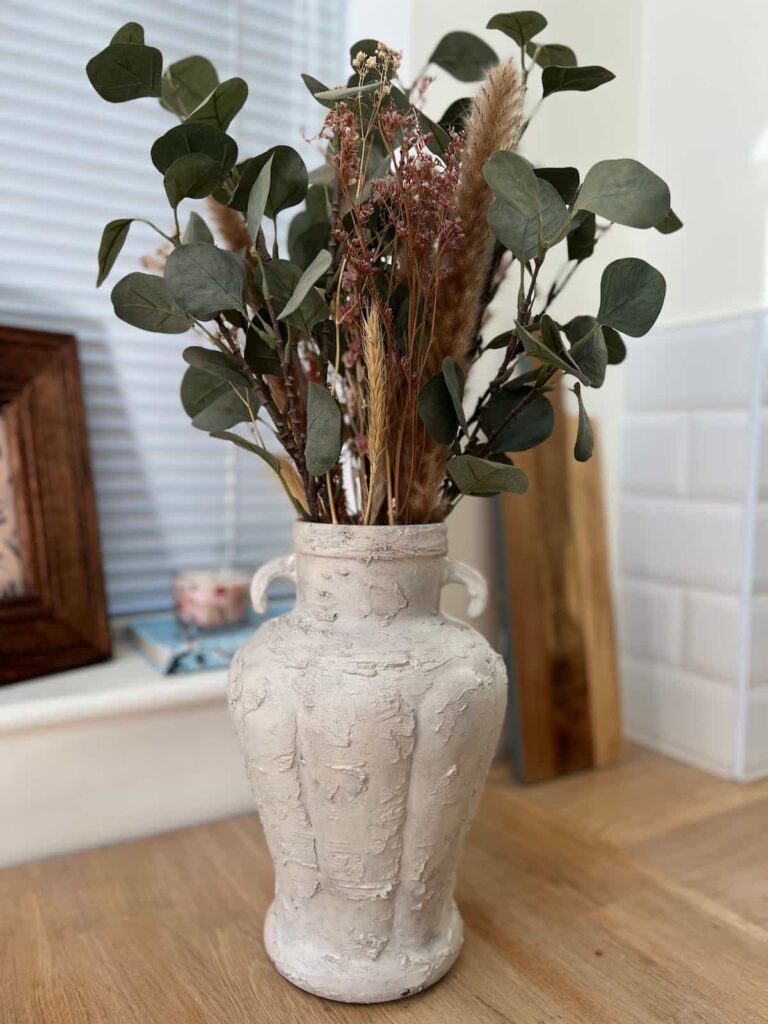 image shows a painted glass vase with flowers.