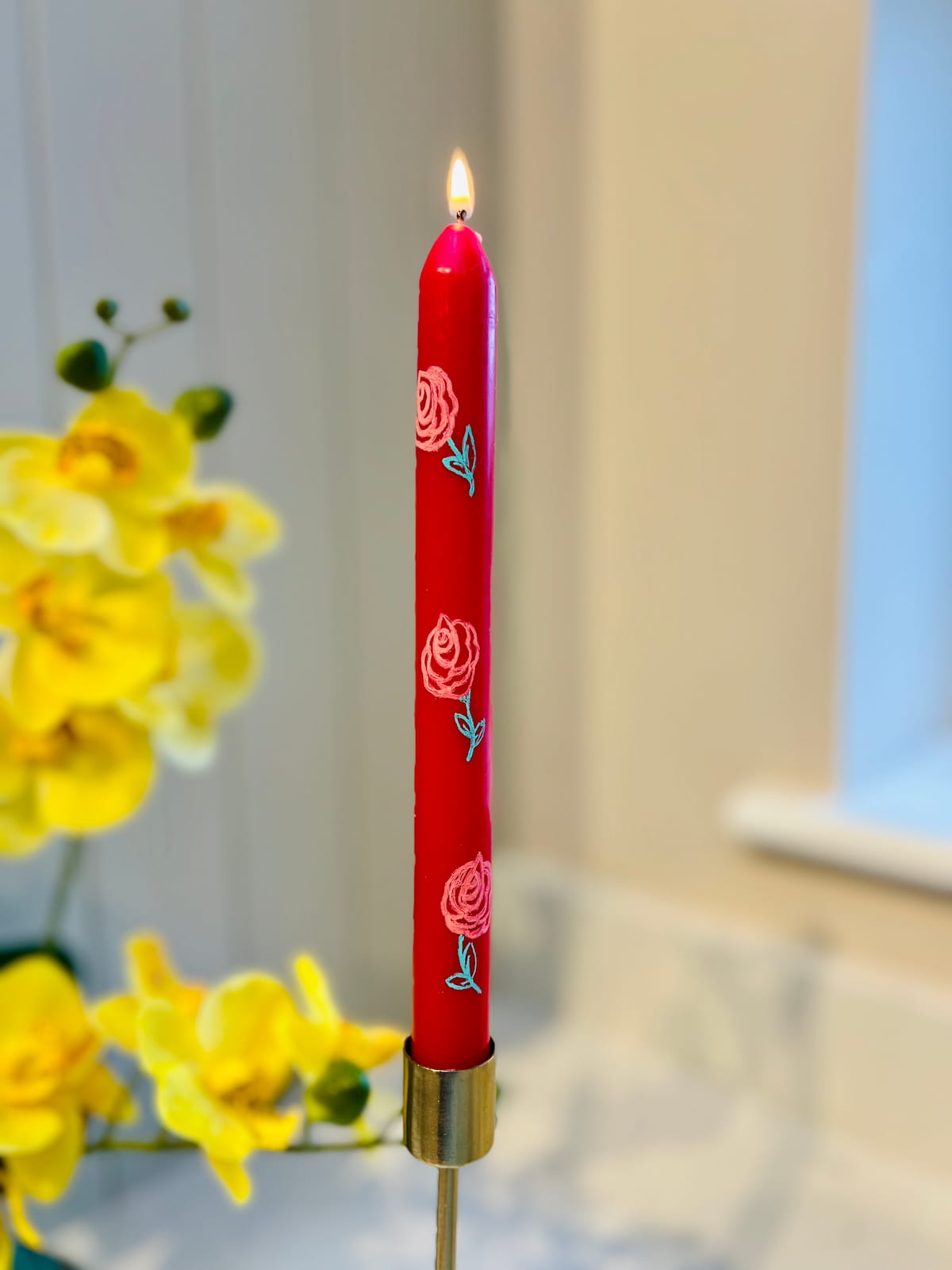 image shows taper candle painted with rose design.