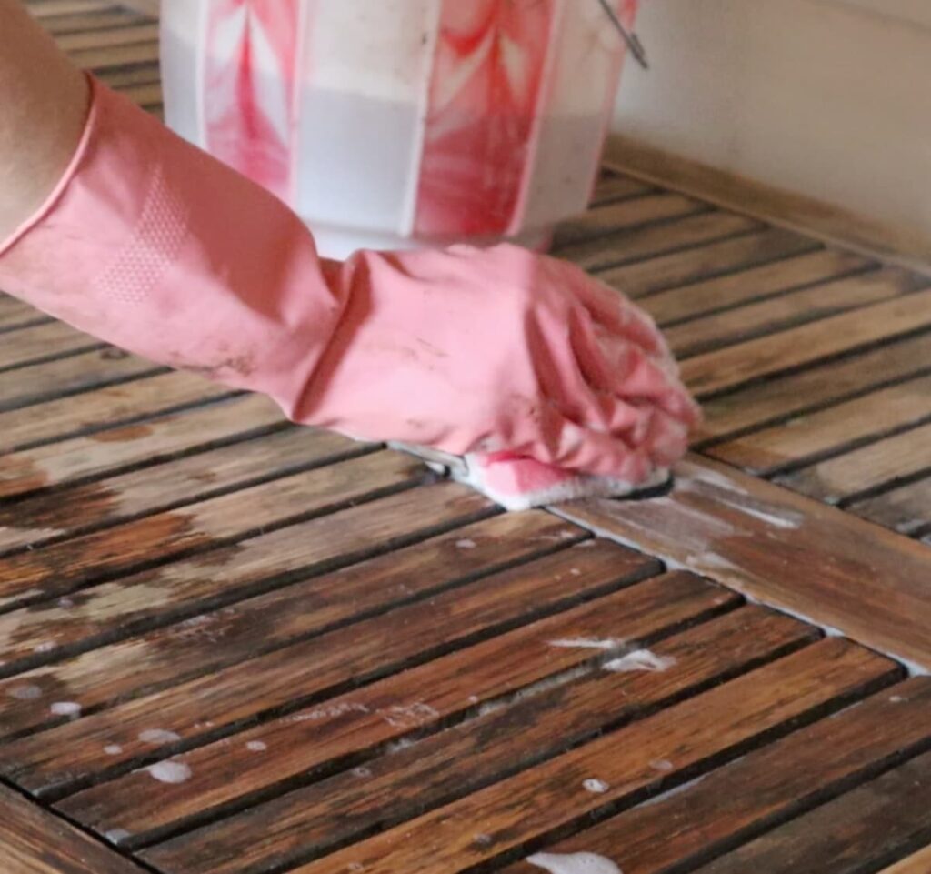 image shows cleaning patio table with gloved hand.